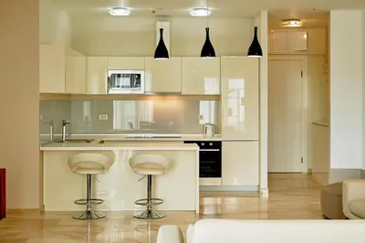 a kitchen with white cabinets and bar stools at Sunrio Apartments in Budva