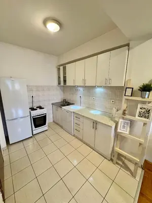 a kitchen with white cabinets and a white refrigerator at Bright & Cozy Urban Apartment in Podgorica