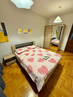 a bedroom with a bed and a large mirror at Bright & Cozy Urban Apartment in Podgorica