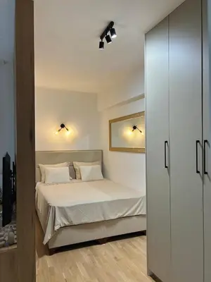 a bedroom with a bed with white sheets and a mirror at Family Homes Bar Apartment in Bar
