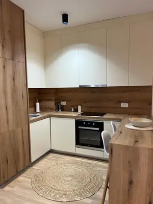 a kitchen with white cabinets and a wooden table at Family Homes Bar Apartment in Bar