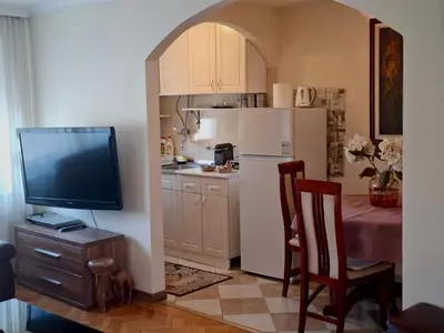 a kitchen with a refrigerator and a table with a chair at Milenijum apartman in Podgorica