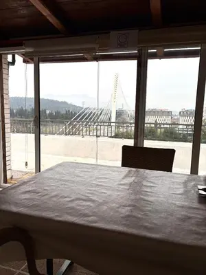 a table in a room with a view of a bridge at Milenijum apartman in Podgorica