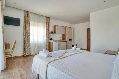 a bedroom with a large white bed and a kitchen at Aqua Lounge Aparthotel Ulcinj in Ulcinj