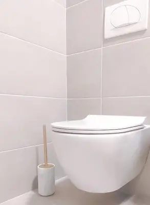a white toilet in a white tiled bathroom at Stylish City Living Elegant One Bedroom Apartment in Podgorica