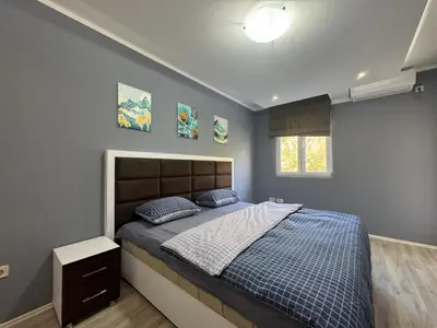a bedroom with a bed with a blue comforter and a window at Lucky Space 3 Apartment in Budva