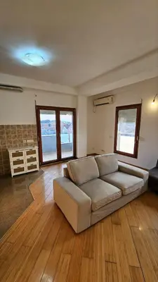 a living room with a couch and wooden floors at OldAirport in Podgorica