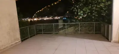 a balcony with a fence and lights at night at Zlatna Guest House in Kotor