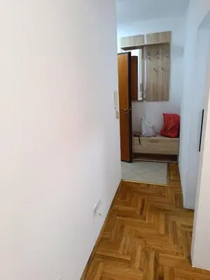 a room with white walls and wooden floors and a bed at Nikola apartment in Podgorica
