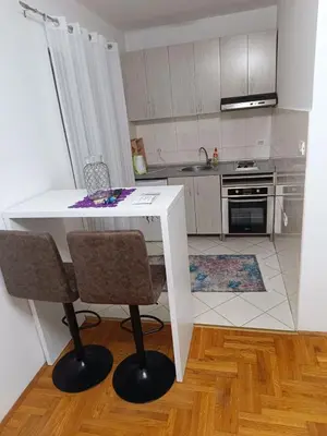 a kitchen with a white table and two chairs at Nikola apartment in Podgorica