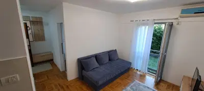 a living room with a blue couch and a window at Nikola apartment in Podgorica