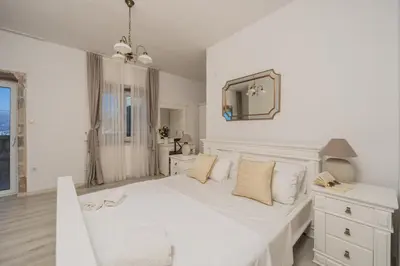 a white bedroom with a white bed and a mirror at Olive Resort in Petrovac na Moru