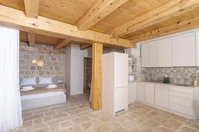 a kitchen with white cabinets and a wooden ceiling at Olive Resort in Petrovac na Moru