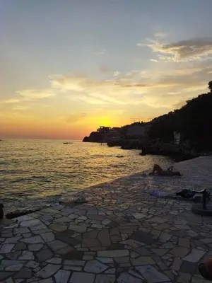 a sunset on a stone beach with the ocean at Beach House Kruče in Ulcinj