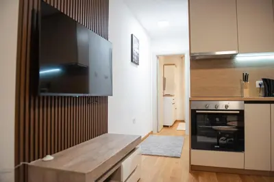 a kitchen with a stove and a tv on the wall at Phenix Apartments Parking FREE in Podgorica