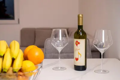 a bottle of wine and two wine glasses on a table at RiverBank Apartmani in Podgorica