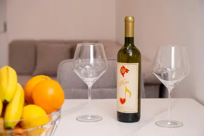a bottle of wine and two wine glasses on a table at RiverBank Apartmani in Podgorica