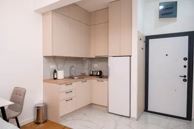a small kitchen with white cabinets and a door open at RiverBank Apartmani in Podgorica