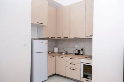 a kitchen with white cabinets and a refrigerator at RiverBank Apartmani in Podgorica