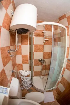 a bathroom with a shower and a toilet and a mirror at Guest House Vucicevic in Budva