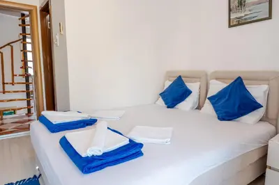 a white bed with blue pillows and towels on it at Guest House Vucicevic in Budva