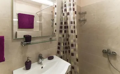 a white bathroom with a sink and a shower at Apartments Location by Chabad House in Becici