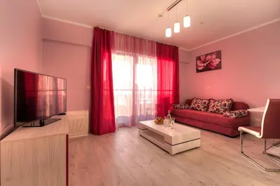 a living room with a red couch and a tv at Apartments Location by Chabad House in Becici