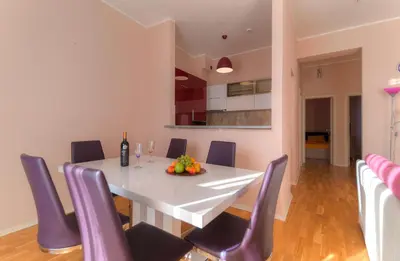 a dining room with a white table and purple chairs at Apartments Location by Chabad House in Becici