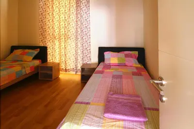 a bedroom with two beds and a door with a window at Apartments Location by Chabad House in Becici