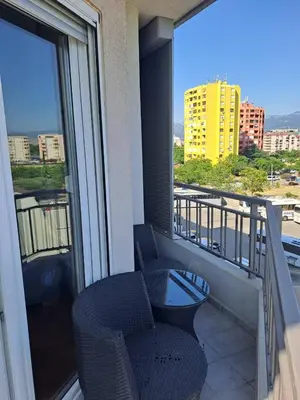 a balcony with two chairs and a view of a building at Sunny Corner Apartment in Podgorica