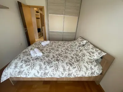 a bedroom with a bed with a gray and white comforter at Sunny Corner Apartment in Podgorica