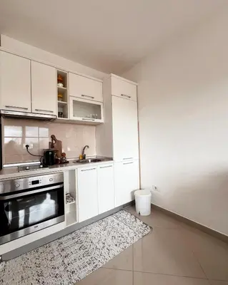 a white kitchen with white cabinets and a rug at Cozy seaside studio in Bar