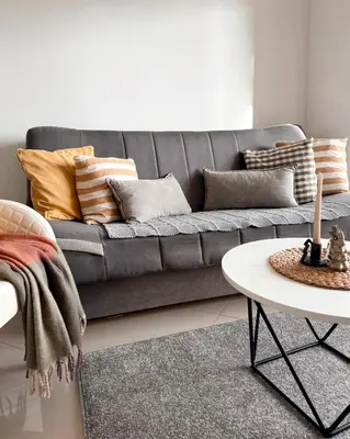 a grey couch with pillows on it in a living room at Cozy seaside studio in Bar