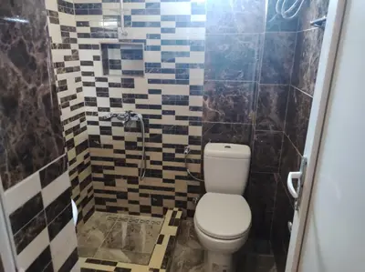 a bathroom with a toilet and a tiled wall at Grandino Rooms & Apartments in Ulcinj