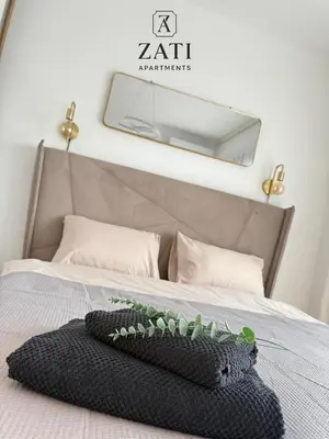a bed with a black blanket and a mirror on the wall at Zati Homes Ulcinj in Ulcinj