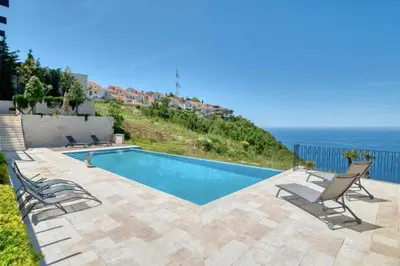 a swimming pool with chairs and the ocean in the background at The View - Apartment with Pool in Blizikuće