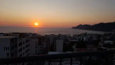 a sunset over the ocean and a city at Apartment Hrubosovic Dobra voda in Dobra Voda