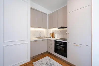 a white kitchen with white cabinets and a stove at Quince Apartments in Podgorica