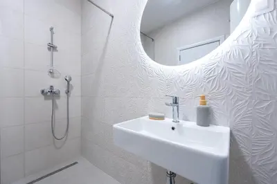 a white bathroom with a sink and a mirror at Quince Apartments in Podgorica