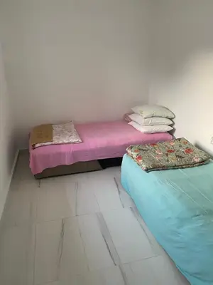 two twin beds in a room with pink and blue at Apartman sa garažom in Sutomore