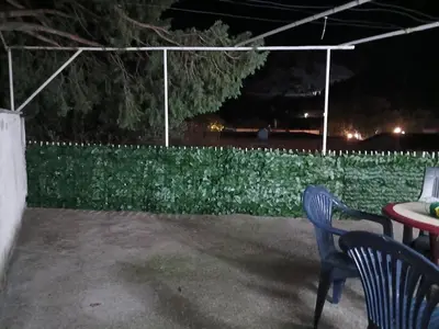 a patio with two chairs and a table at night at Apartman sa garažom in Sutomore