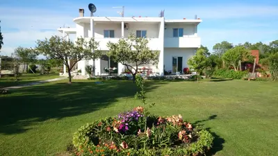 a white house with a green yard with flowers at Luce di Sole Apartment in Ulcinj