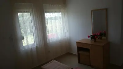 a room with two windows and a dresser with a mirror at Luce di Sole Apartment in Ulcinj