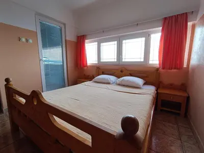 a bedroom with a wooden bed with red curtains at Apartmani Šaltić in Sutomore