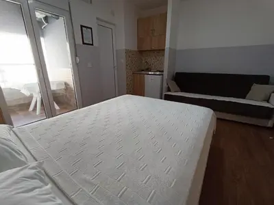 a bedroom with a white bed and a living room at Apartmani Šaltić in Sutomore