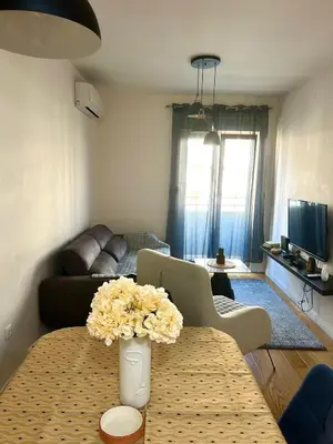 a living room with a table with a vase of flowers at Elegant apt in Central Point in Podgorica