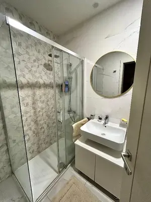 a bathroom with a shower and a sink and a mirror at Elegant apt in Central Point in Podgorica