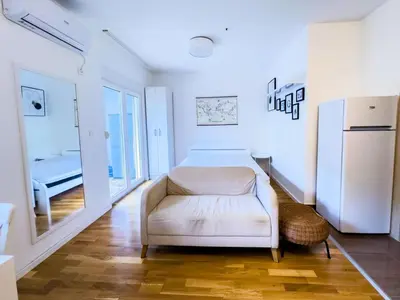 a white room with a white chair and a refrigerator at Pela's Apartment in Budva