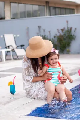 a woman holding a little girl sitting in a swimming pool at Hotel Lajka Luxury in Ulcinj