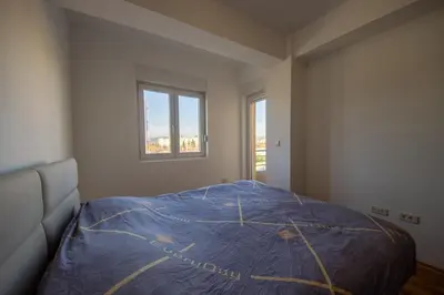 a bedroom with a bed with a blue blanket on it at Sunbright Metropolitan in Podgorica